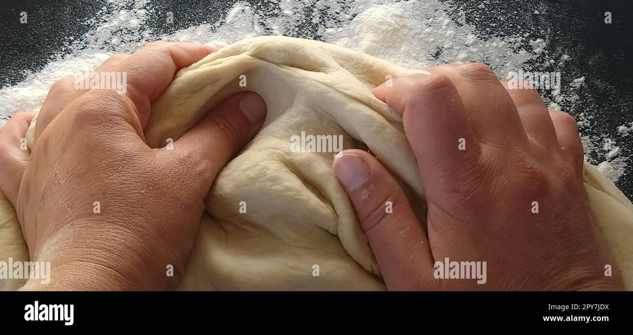 Die Hände kneten den Teig. Die Frau knete Teig zum Backen oder Knödel. Herstellung von Mehl, Wasser und Eimasse für die thermische Verarbeitung. Koch-Hände Stockfoto