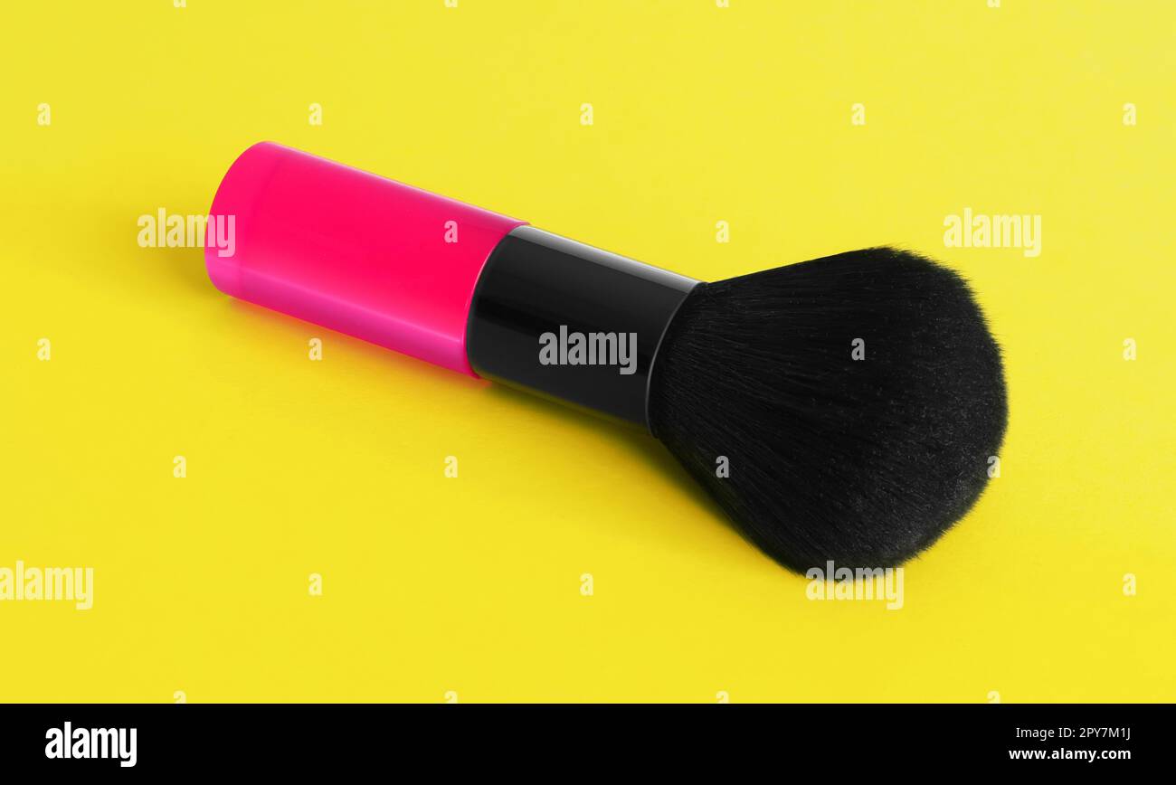 Eine rosafarbene Make-up-Bürste auf gelbem Hintergrund Stockfoto
