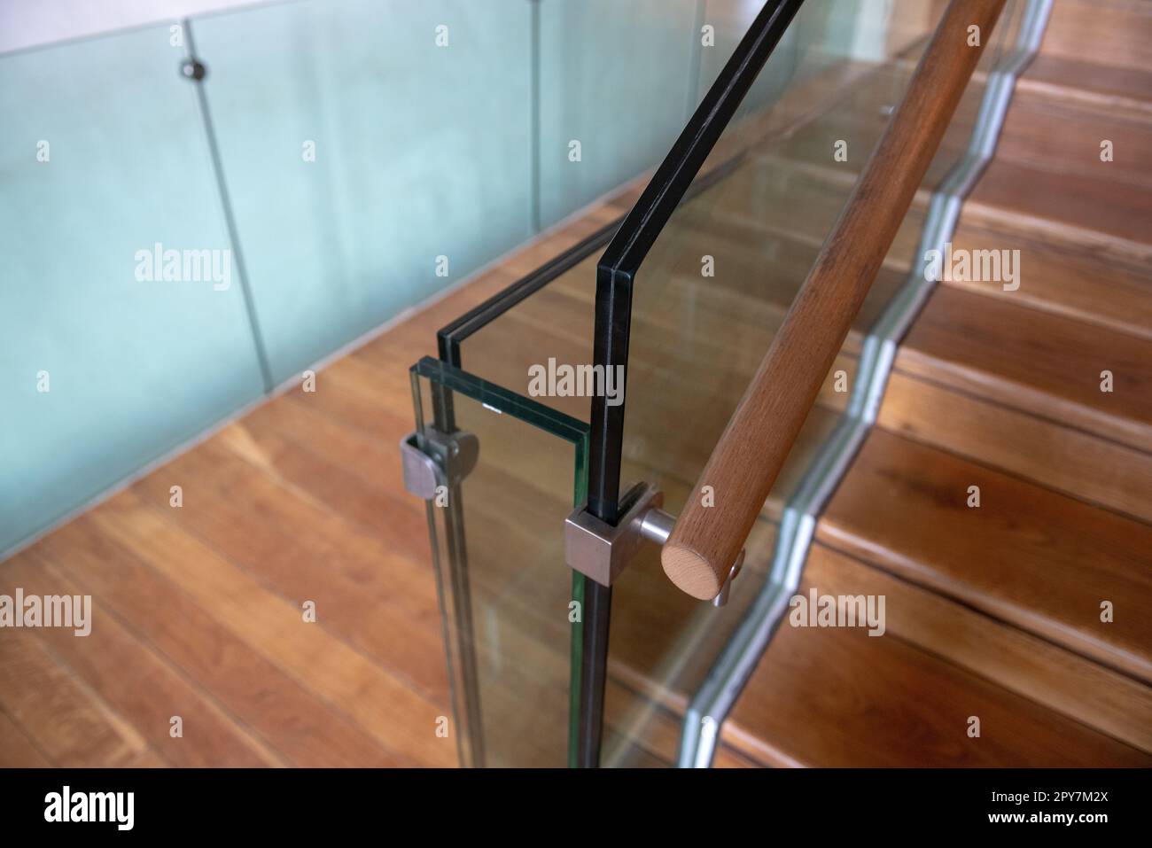 Detail einer modernen Treppe mit Glas, Stahl und Holzhandlauf. Die Attika aus doppelt bruchsicherem Glas. Stockfoto