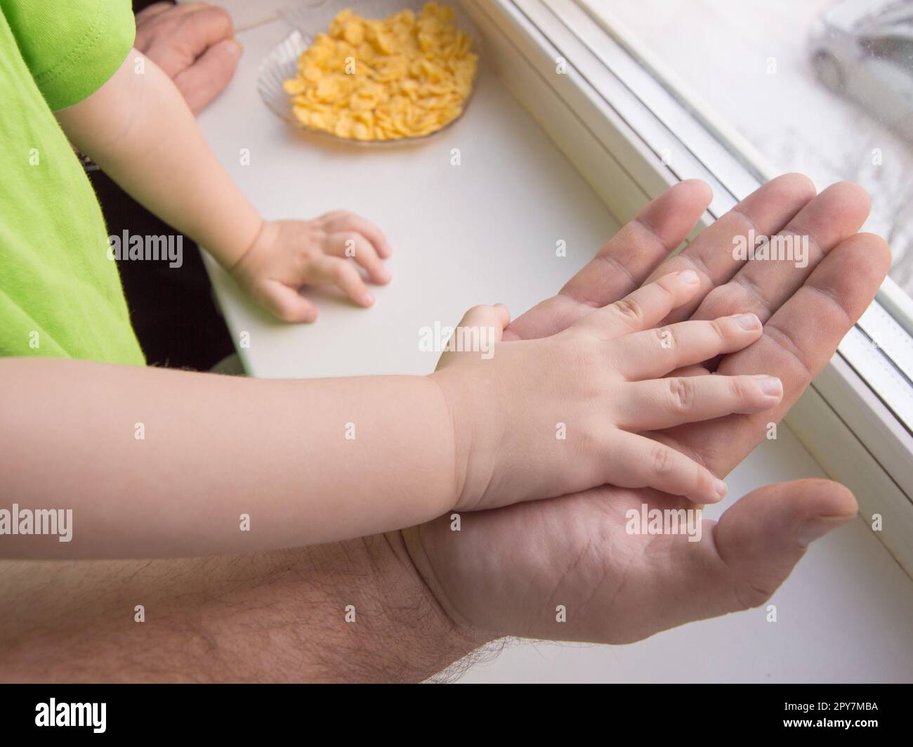 Die Hand des Kindes liegt auf der Handfläche eines erwachsenen Mannes, Kinderschutz Stockfoto
