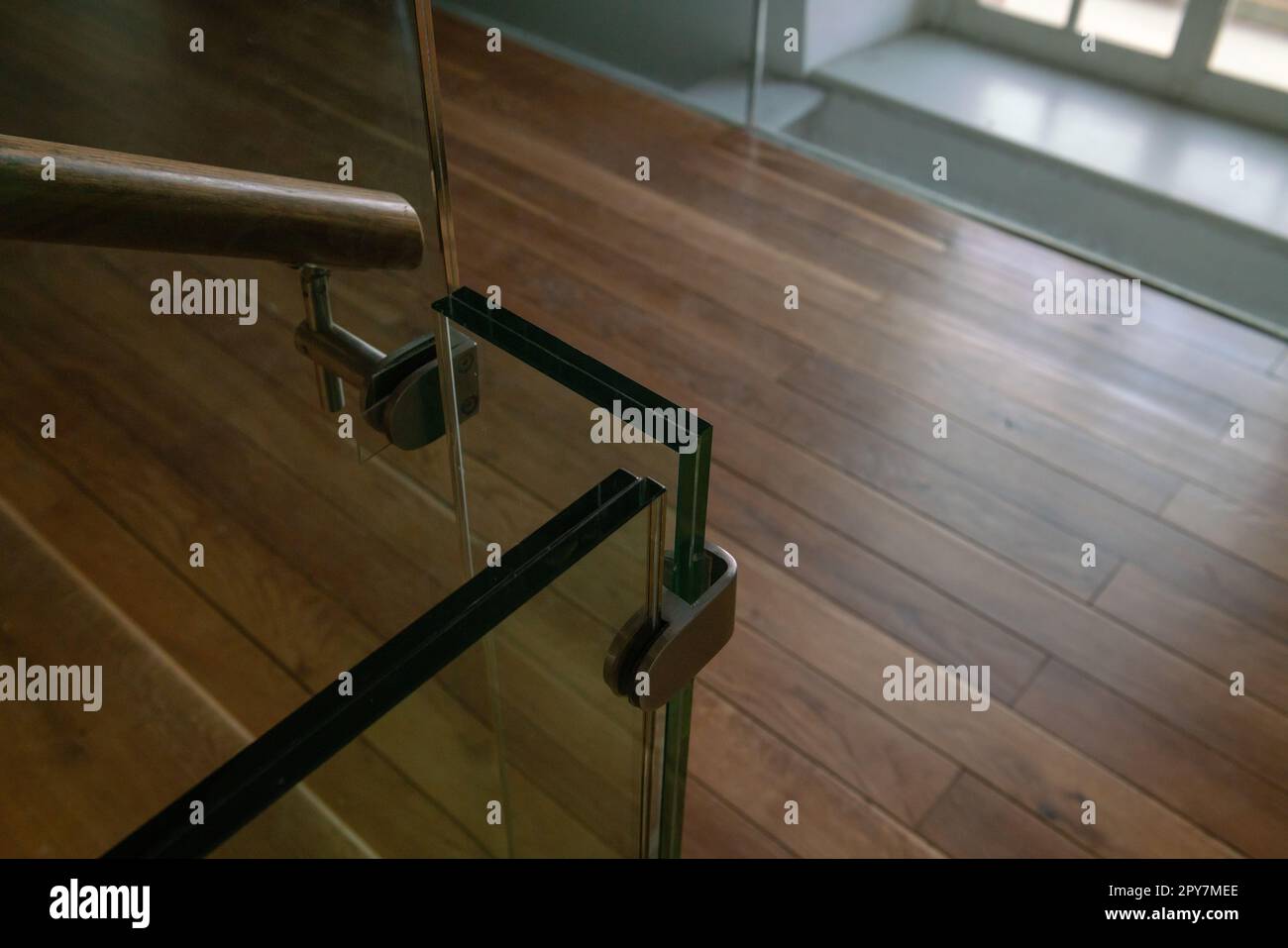 Detail einer modernen Treppe mit Glas, Stahl und Holzhandlauf. Die Attika aus doppelt bruchsicherem Glas. Stockfoto