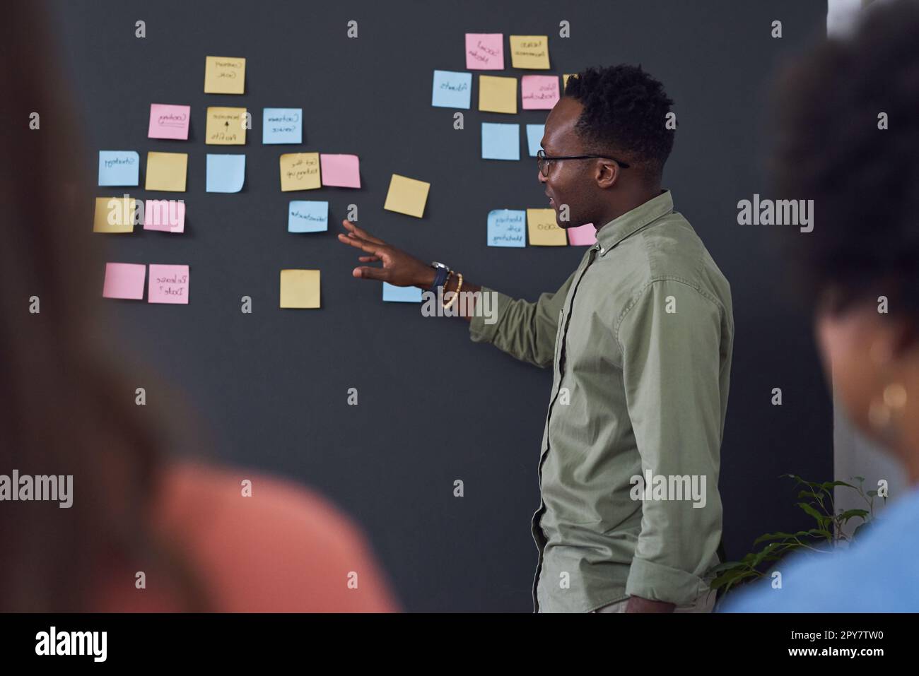 Lassen Sie uns hier über diese Idee sprechen. Ein Team junger Geschäftsleute, das ein Brainstorming in einem modernen Büro durchführt. Stockfoto