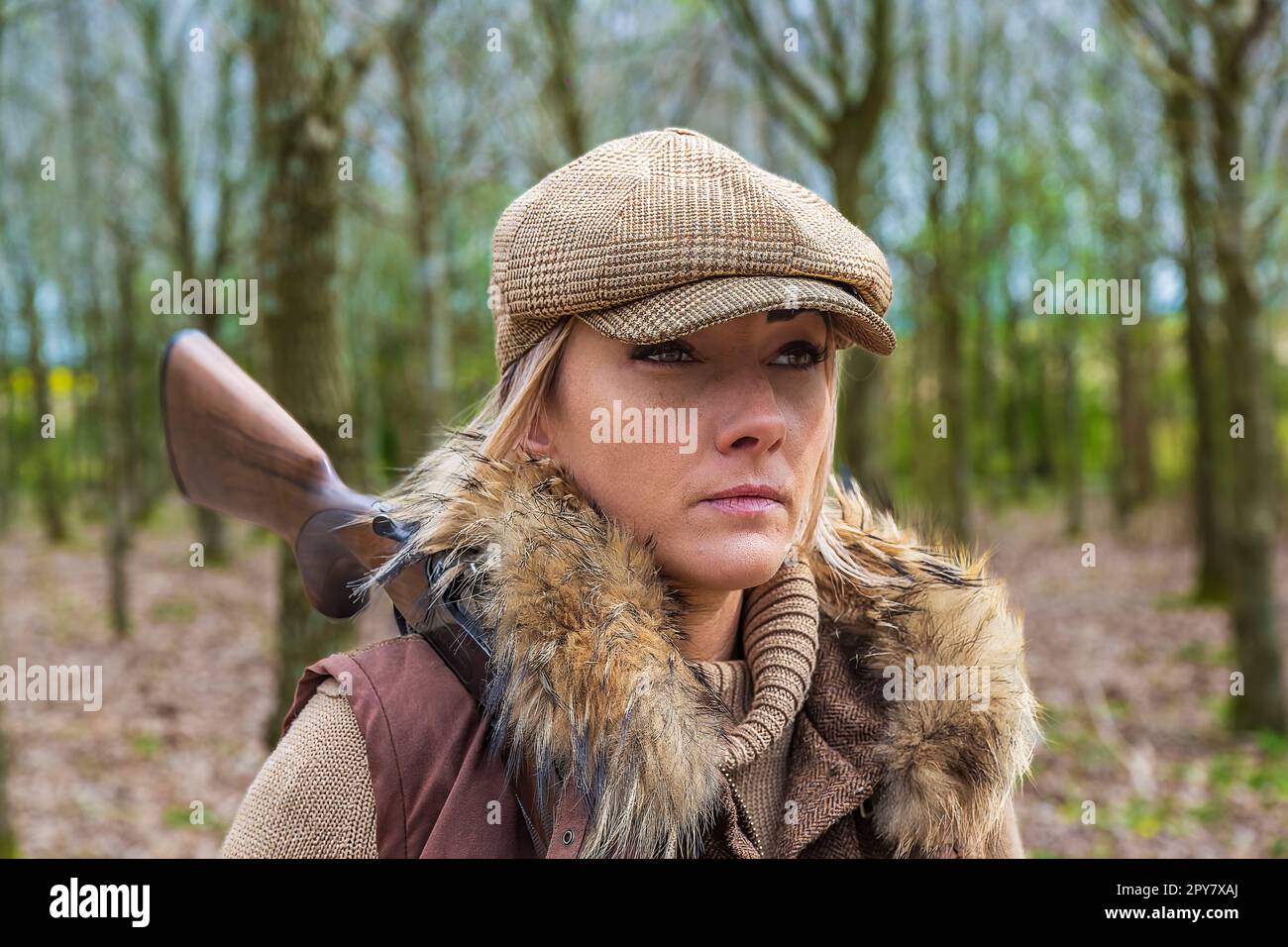 Eine über 30-jährige Frau, die im späten Frühling im Wald schießt, mit einer Schrotflinte, die sich darauf vorbereitet, Tauben zu erschießen Stockfoto