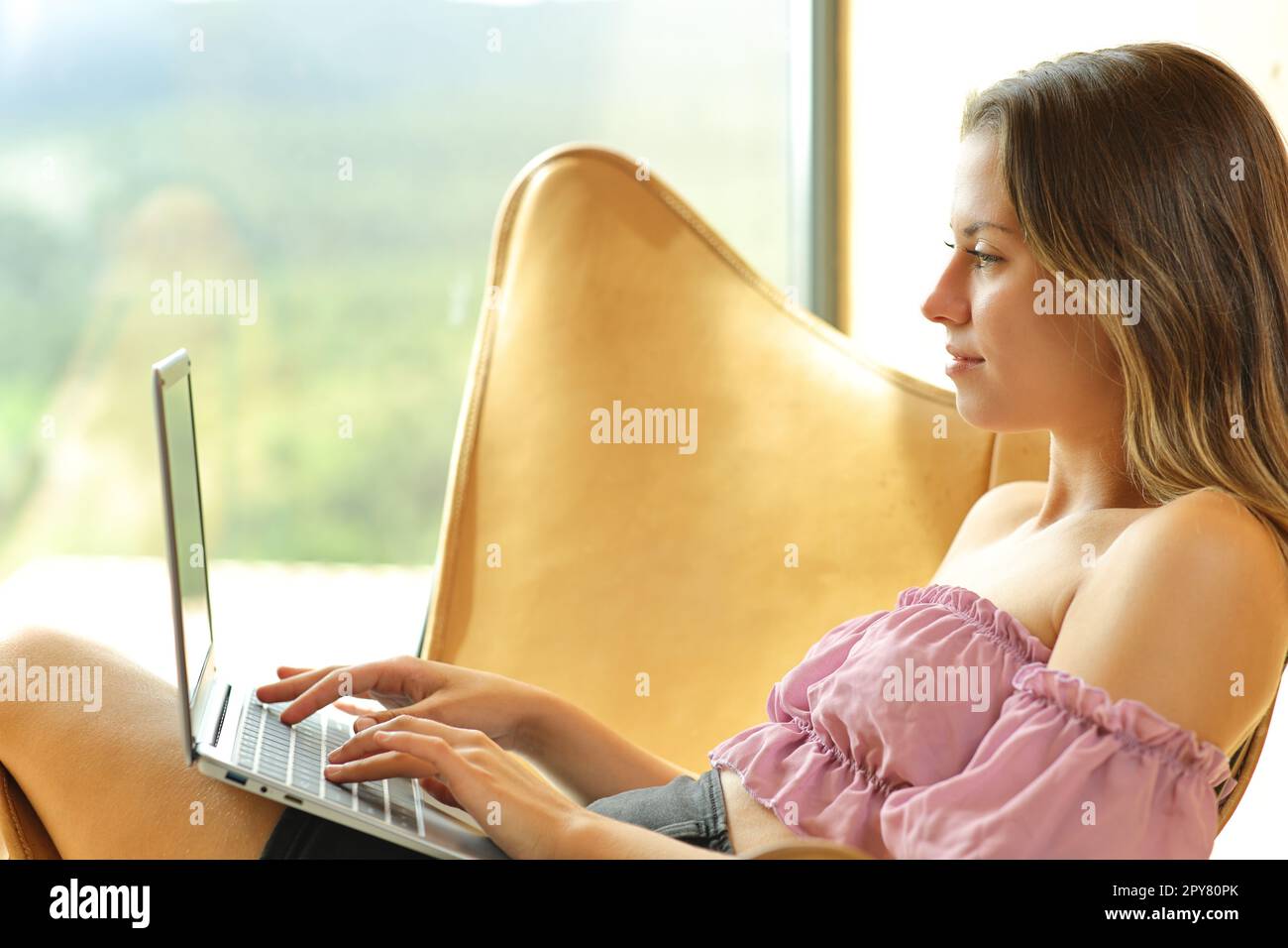 Teenager, die zu Hause einen Laptop auf einem Stuhl benutzen Stockfoto