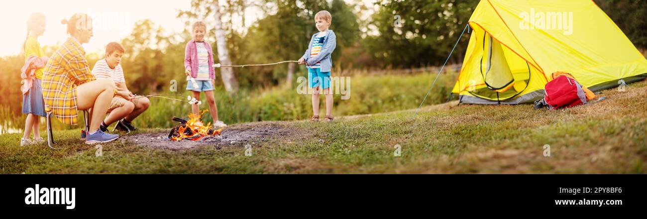 Gruppe von Leuten, die in der Nähe des Lagerfeuers sitzen und Marshmallows kochen. Stockfoto