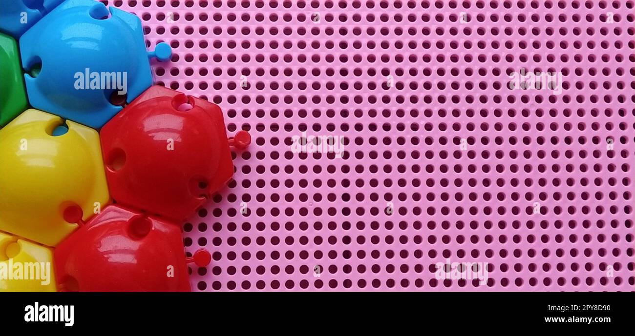 Brettspiel - ein Mosaik zur Entwicklung der mentalen und kreativen Fähigkeiten des Kindes. Rosafarbene Kunststoffbox mit Löchern. Auf der linken Seite mehrfarbige Chips und Formen, um eine Darstellung zu erstellen. Stockfoto