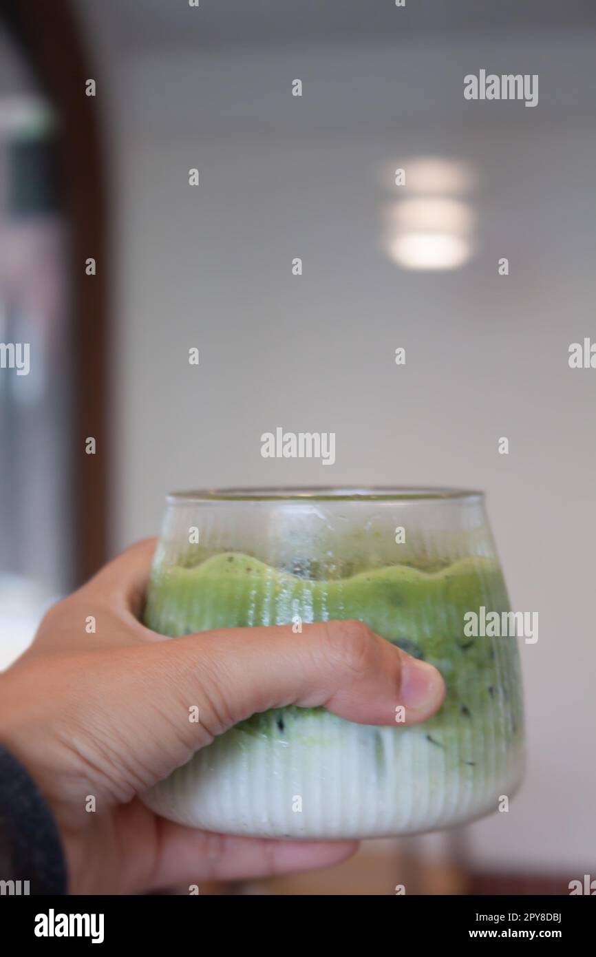 Handgehaltener Eistee mit Matcha-Grün Stockfoto