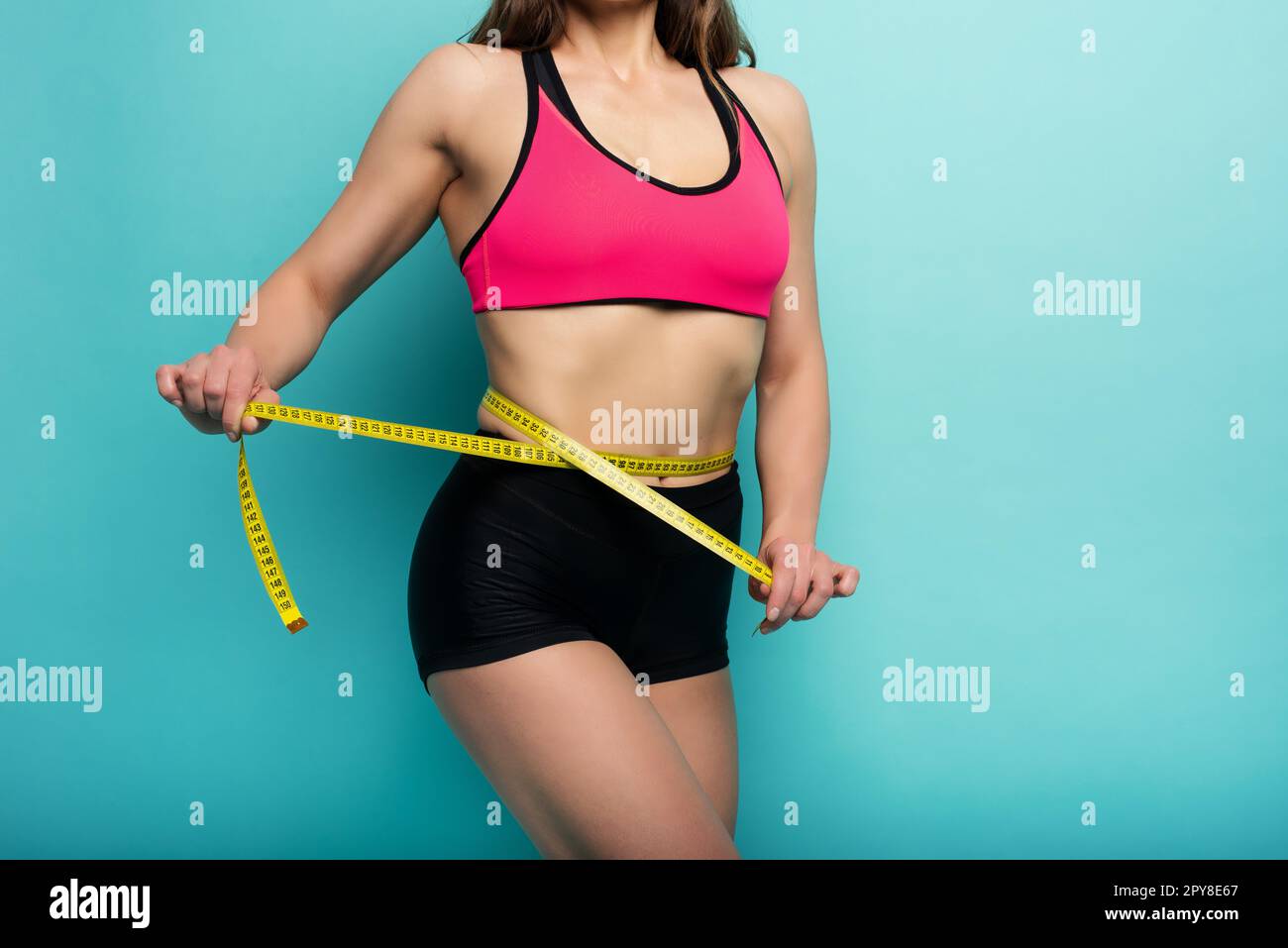 Determinated Sport Frau hat eine ausgezeichnete körperliche Form und messen mit dem Meter. Cyanfarbener Hintergrund Stockfoto