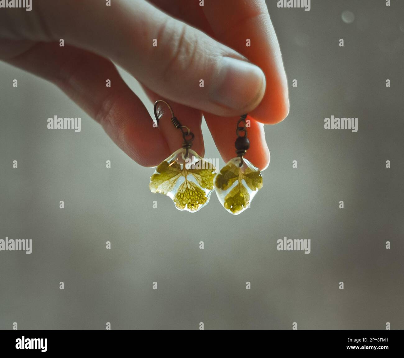 Nahaufnahme Dame zeigt kleinen Ohrring mit Blättern Konzeptfoto Stockfoto