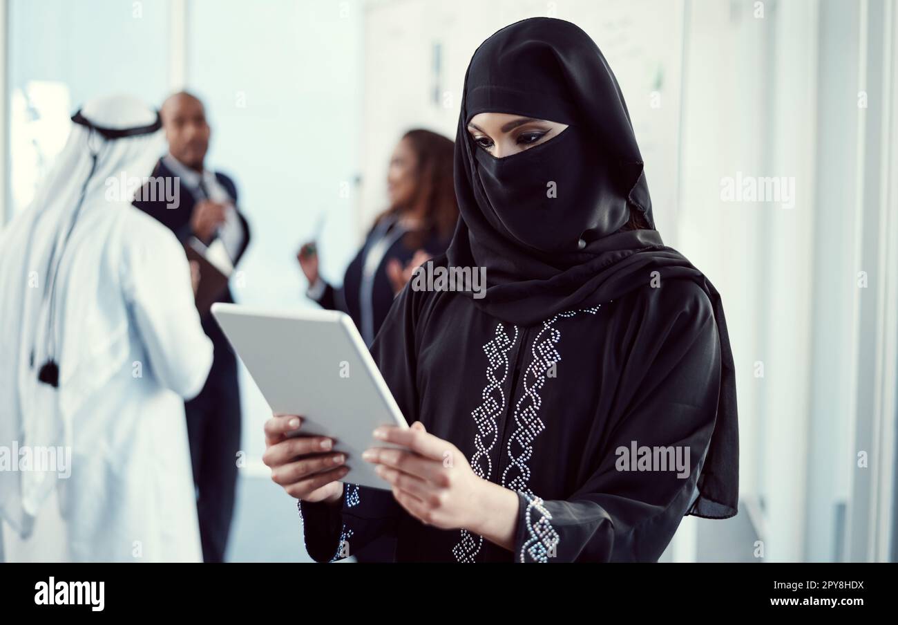 Effizient arbeiten, um die Arbeit zu erledigen. Eine attraktive junge arabische Geschäftsfrau, die mit ihren Kollegen im Büro an einem Tablet arbeitet Stockfoto