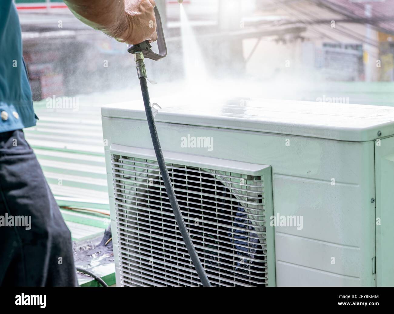 Klimaanlagenreinigung durch einen Mann. Der Techniker reinigt die Kondensatoreinheit der Klimaanlage durch Spritzen von Wasser. Wartungsservice für Klimaanlagen zu Hause oder im Büro. Arbeiter, der für die Wartung von Wechselstrom arbeitet. Stockfoto