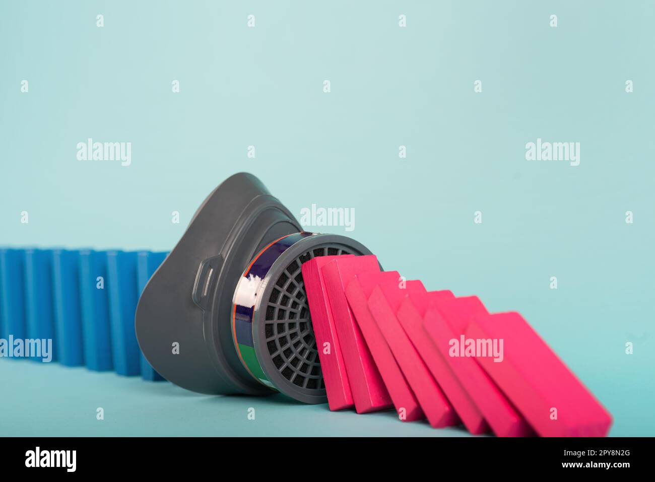 Konzept der covid19 Coronavirus Pandemie mit fallenden Kette wie ein Domino-Spiel. Ansteckung und Infektionsverlauf durch eine Maske gestoppt. Cyanfarbener Hintergrund Stockfoto