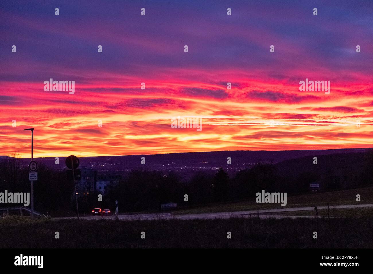 Wunderschöner rosa und roter Sonnenuntergang über den Feldern und einer Kleinstadt Stockfoto