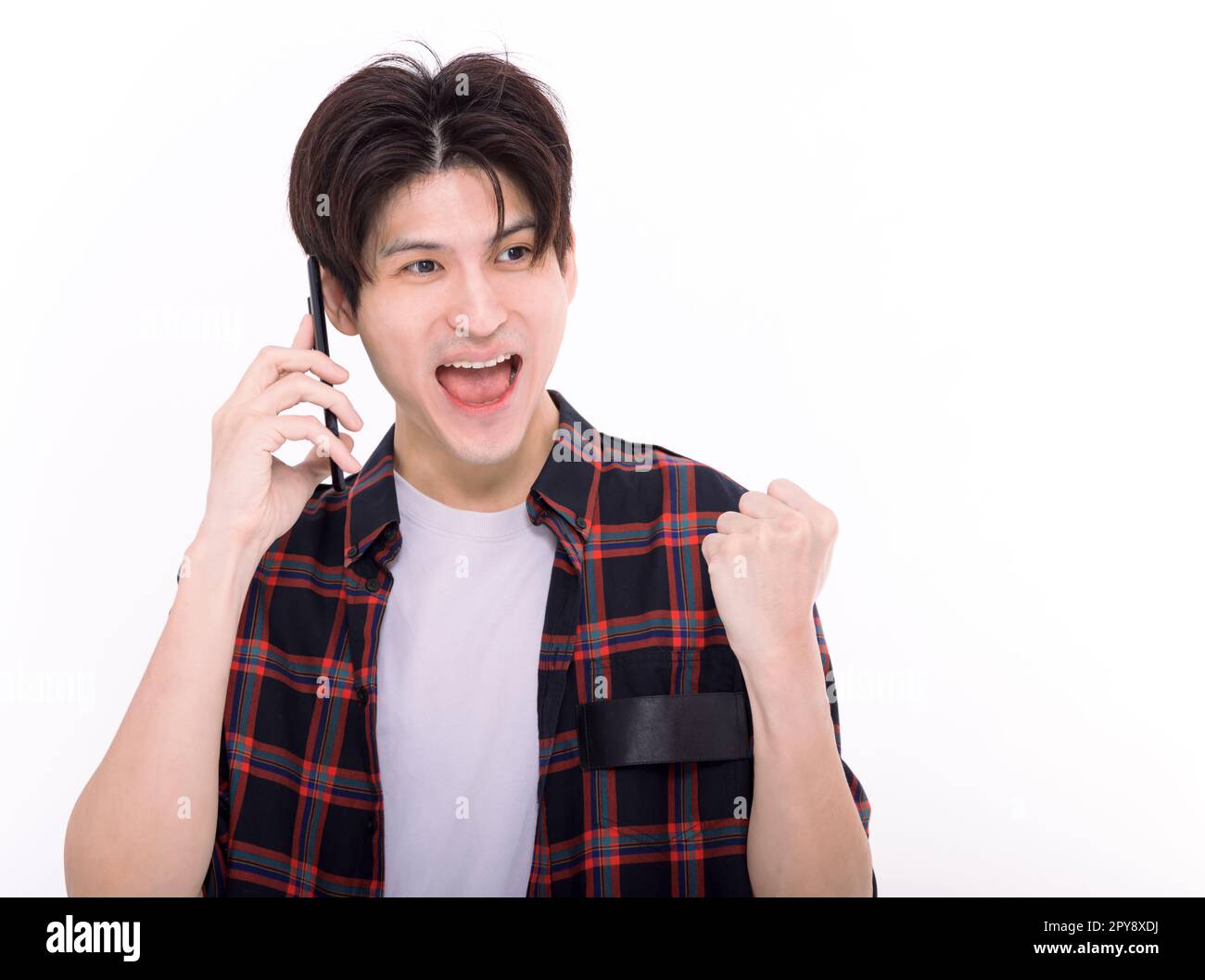 Glücklicher junger Mann, der am Telefon spricht und ja-Gesten zeigt Stockfoto