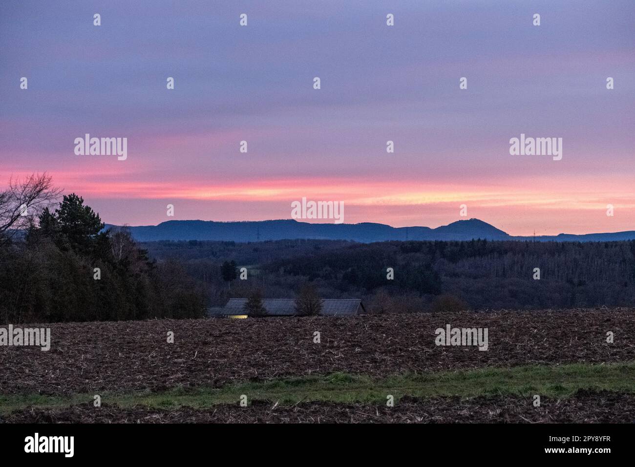 Wunderschöner rosa und roter Sonnenuntergang über den Feldern und einer Kleinstadt Stockfoto