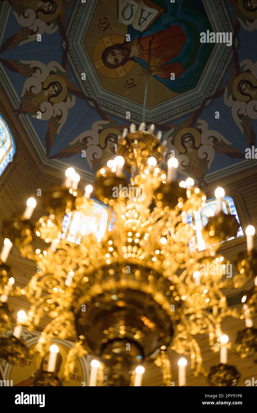 Blick auf die gemalte Kathedrale in einer orthodoxen Kirche vor dem Hintergrund eines glühenden Kronleuchters. Stockfoto