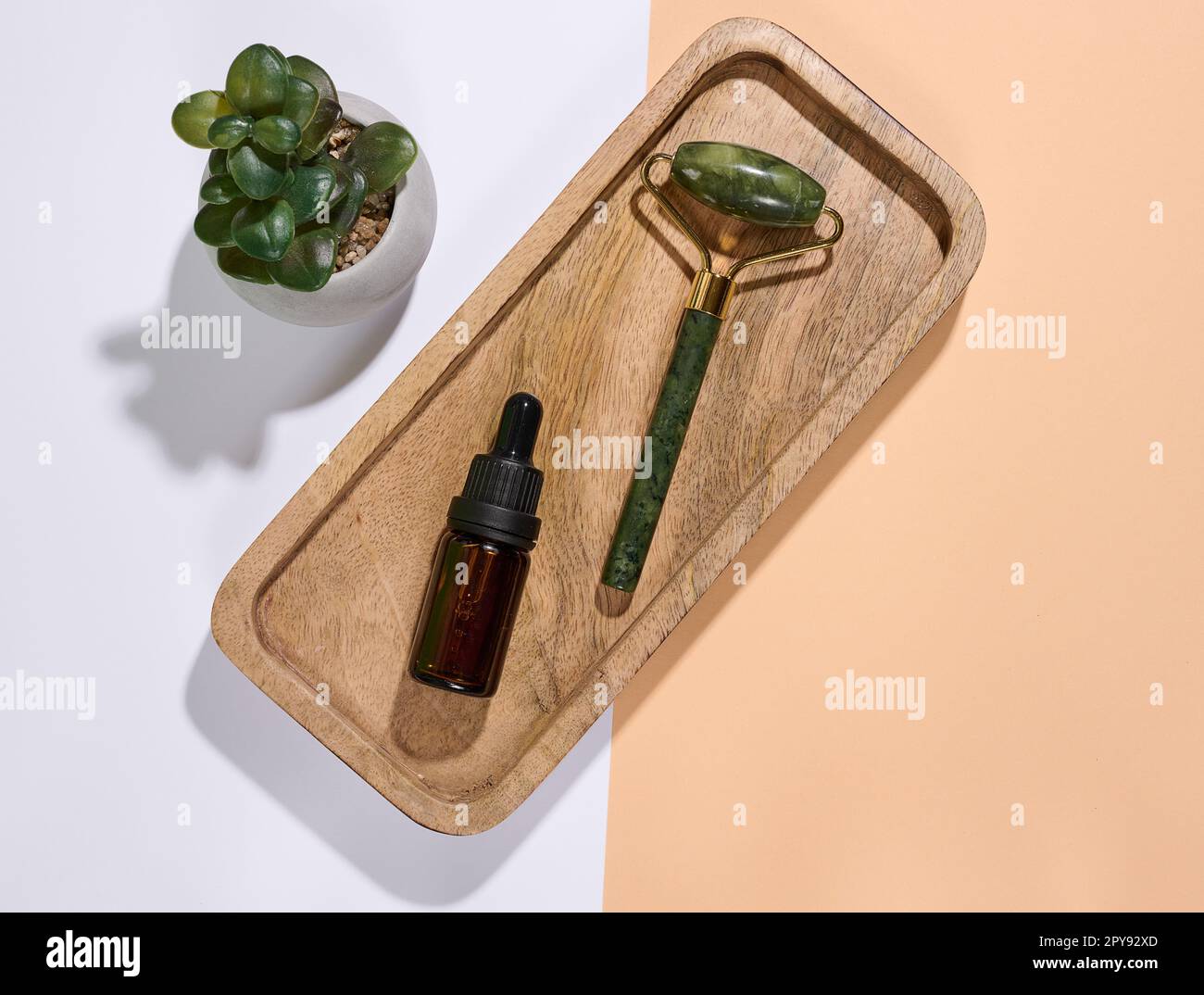 Handmassagegerät für das Gesicht und braune Glasflasche mit Tropfen auf Marmorplatte, Draufsicht Stockfoto