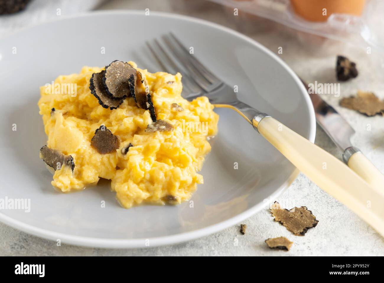 Rühreier mit frischen schwarzen Trüffeln aus Italien, serviert auf einem Teller aus nächster Nähe, Gourmet-Frühstück Stockfoto