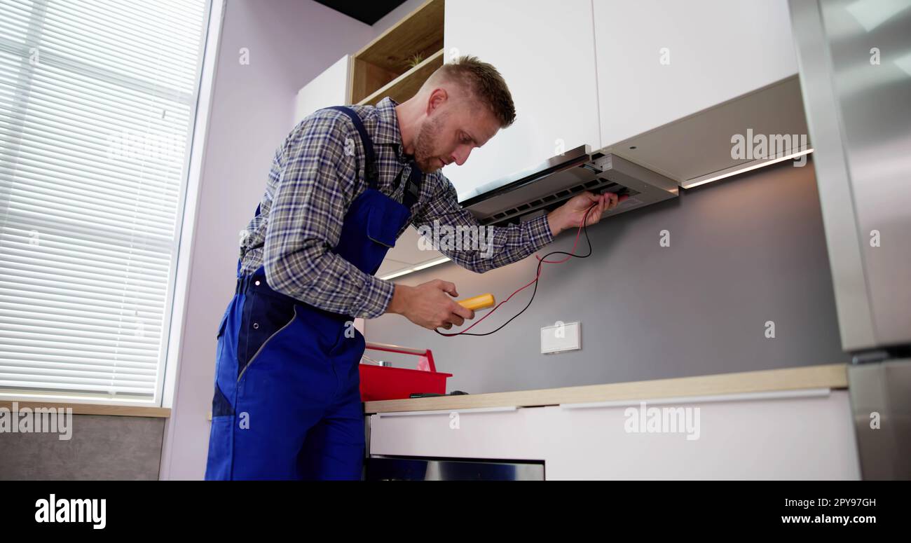 Männlicher Mitarbeiter In Der Gesamten Küchenhaube Mit Multimeter Stockfoto