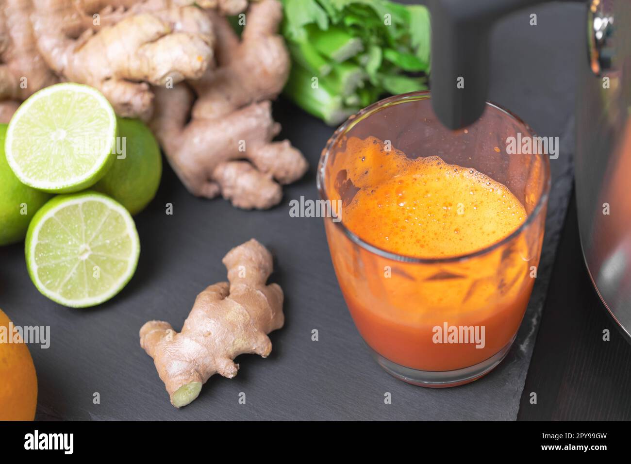 Drücken Sie Karottensaft mit Entsafter gesunde Zitrusfrüchte im Hintergrund. Einnahme Vitamine Entgiftung, gesunde Ernährung und Lebenskonzept. Stockfoto