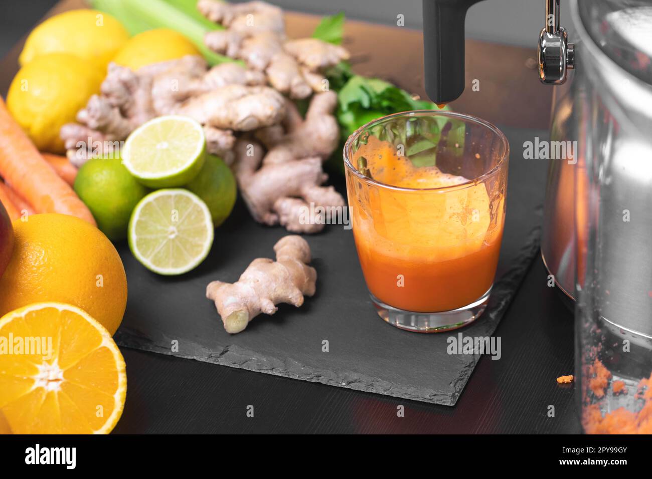 Drücken Sie Karottensaft mit Entsafter gesunde Zitrusfrüchte im Hintergrund. Einnahme Vitamine Entgiftung, gesunde Ernährung und Lebenskonzept. Stockfoto