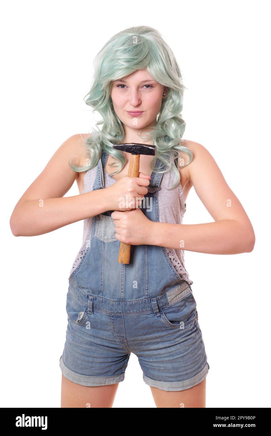 Emanzipierte junge Frau mit grünen Haaren und Jeans Latzhose holding Hammer Stockfoto