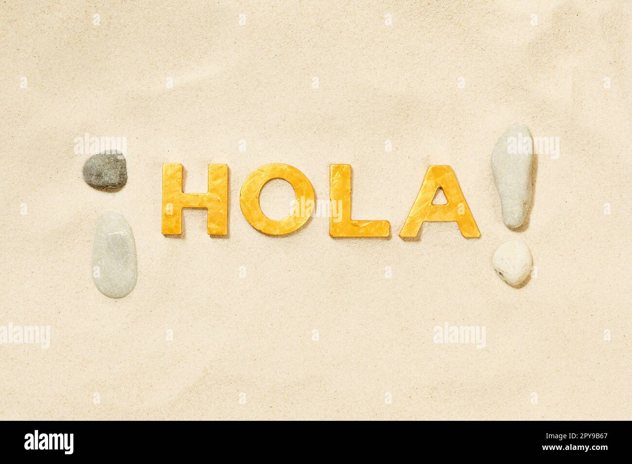 Hola! Nein! - Spanische Begrüßung mit goldenen Buchstaben im weißen Sand Stockfoto
