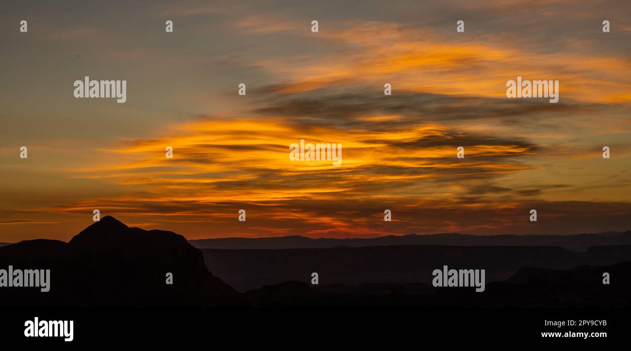 Orangefarbene und graue Wolken schwirren bei Sonnenuntergang über der Wildnis von Big Bend Stockfoto