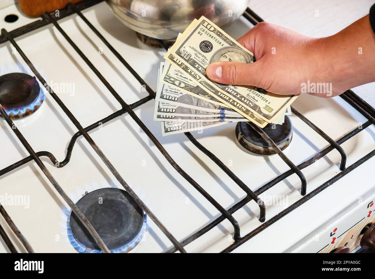 Zahlung von Versorgungsleistungen. Dollarscheine werden in der Nähe eines brennenden Gasbrenners in den Händen gehalten. Das Konzept der Erhöhung der Kosten für die Erdgasversorgung und -Bezahlung. Stockfoto