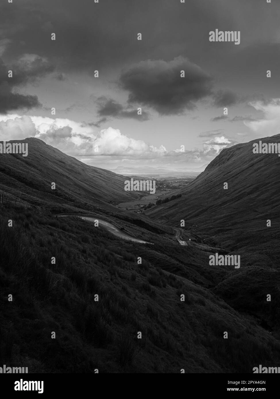 Ein Blick auf den Wild Atlantic Way in Irland, der sich durch ein Tal zwischen zwei Bergen schlängelt, an einem Tag mit aus und Regen. Auf dem irischen Land. Stockfoto