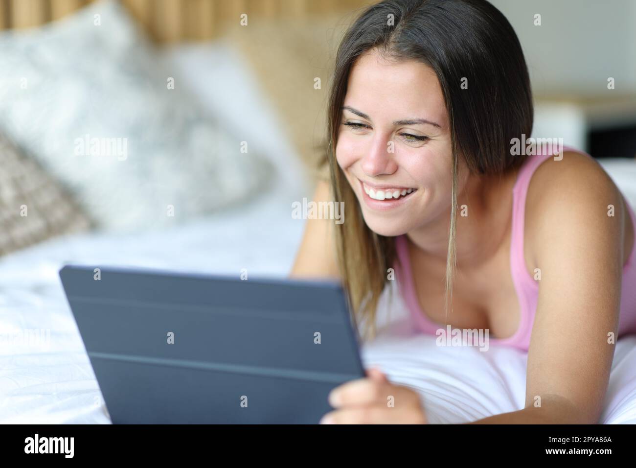 Glücklicher Teenager, der ein Tablet im Bett benutzte Stockfoto