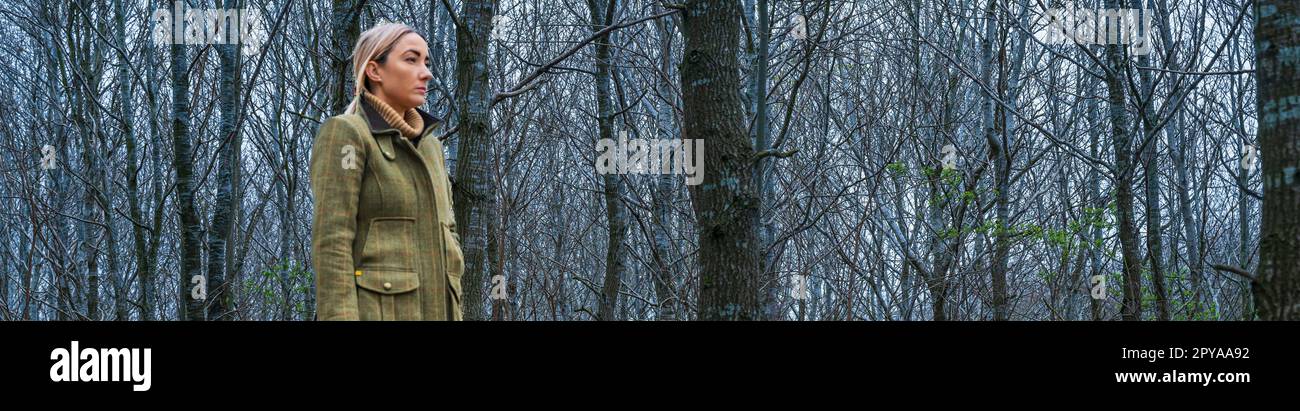 Eine über 30-jährige Frau, die abends im Wald mit einer Schrotflinte schießt Stockfoto