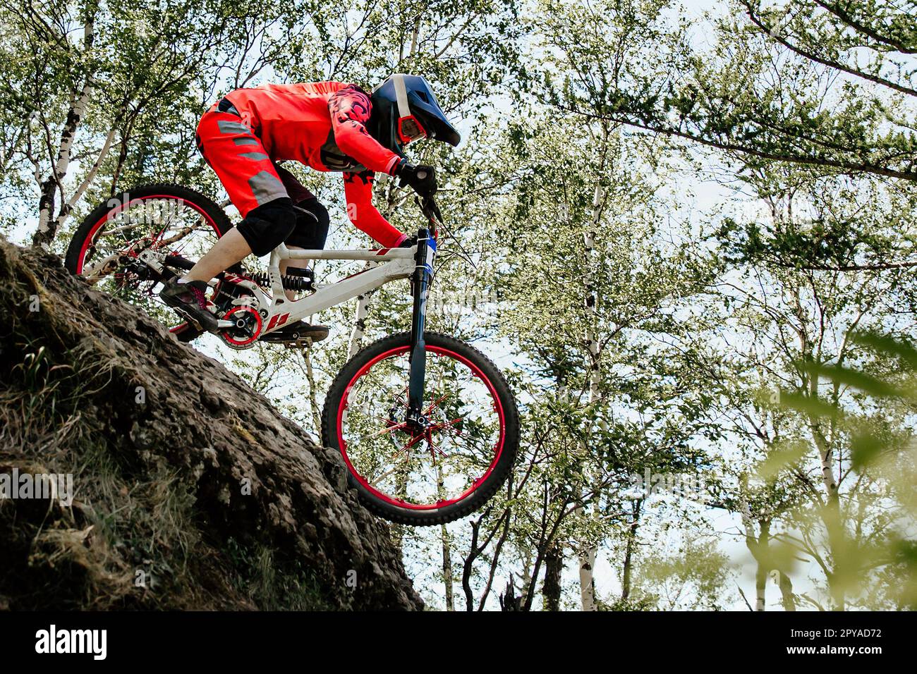 Weibliche Rennradfahrerin, die im Wald ein steiles Abwärtsrennen fährt, Sommer-Mountainbike-Meisterschaft Stockfoto