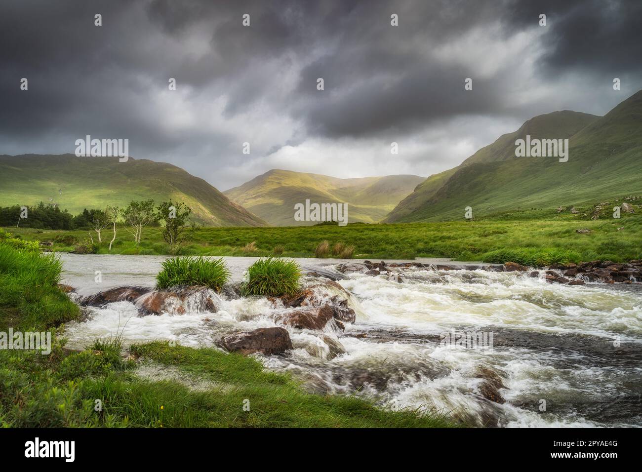 Bundoragha River mit kleinen Wasserfällen und Bergketten im Hintergrund, Irland Stockfoto