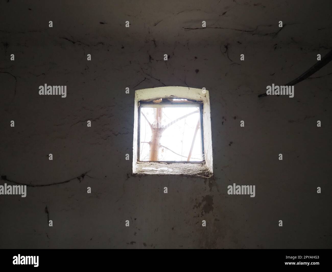 Ein kleines Fenster oben an der Wand. Gruselige Wände mit Spinnweben. Ein alter Kirchenwohnheim. Halloween oder Spukort. Gefängniszelle mit Folterseilen. Visionen und eine Welt voller Halluzinationen Stockfoto