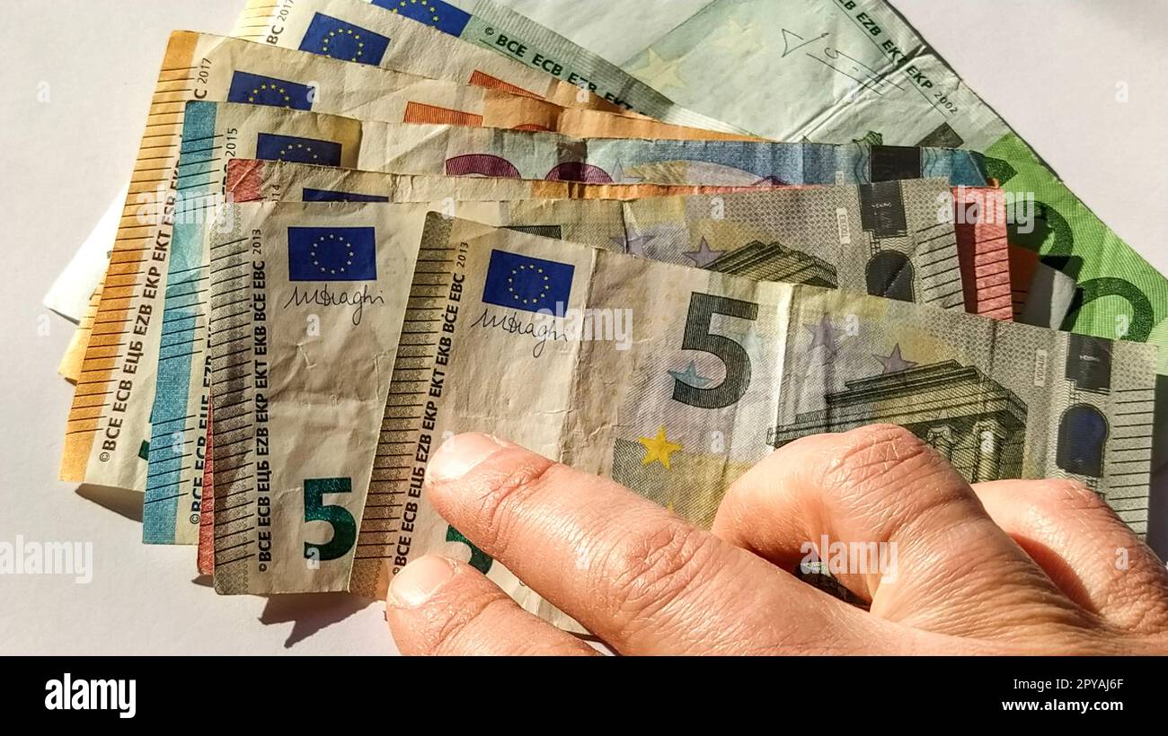 Euro-Papiernoten. Europäische Währung auf weißem Hintergrund. Hand und Finger einer älteren Person oder einer Frau mittleren Alters auf Geld. Banknoten der Zentralbank für 5, 10, 20, 50 und 100 Stockfoto