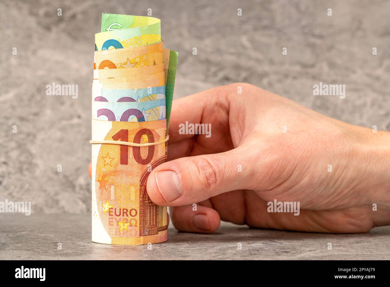 Handgehaltene Rolle von Euro-Banknoten mit einem Gummiband Stockfoto
