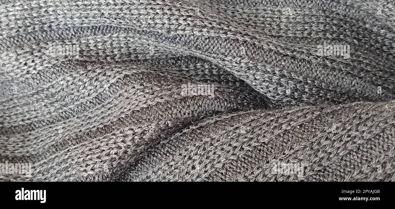 Strickprodukt. Schwarzweißfoto. Schlaufen und Struktur eines Strickpullover-Nahaufnahme. Weben von Wolle und Acrylfäden. Gewerbliche Herstellung von Freizeitkleidung. Schwarzweiß. Soft-Focus-Banner Stockfoto