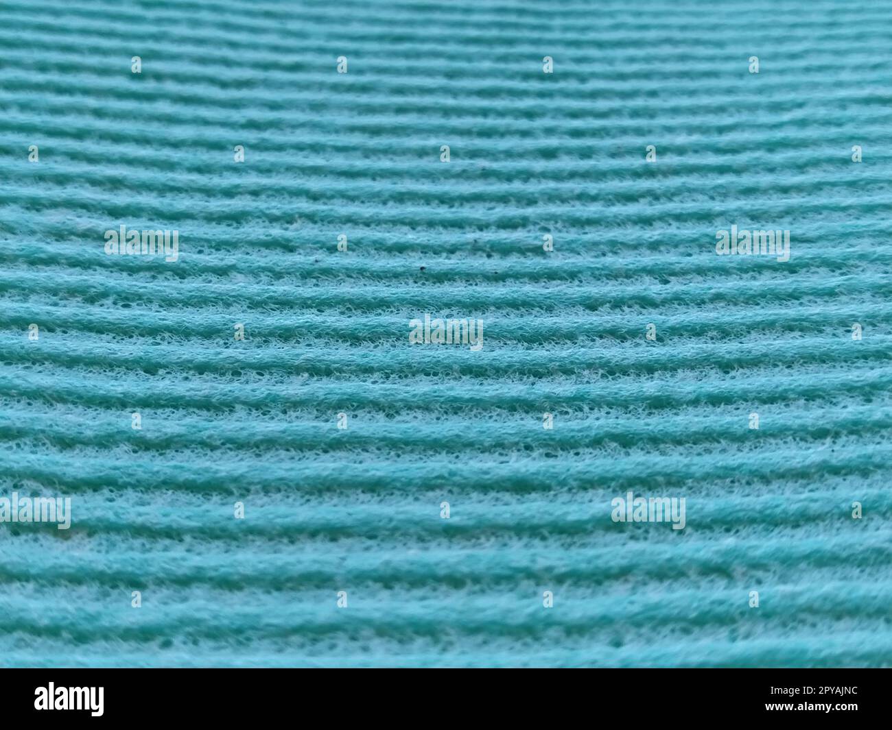 Ein grüner oder aquatisch gerippter Streifen. Geschirrspülschwamm oder Mikrofasertuch – Nahaufnahme. Weichzeichner Stockfoto