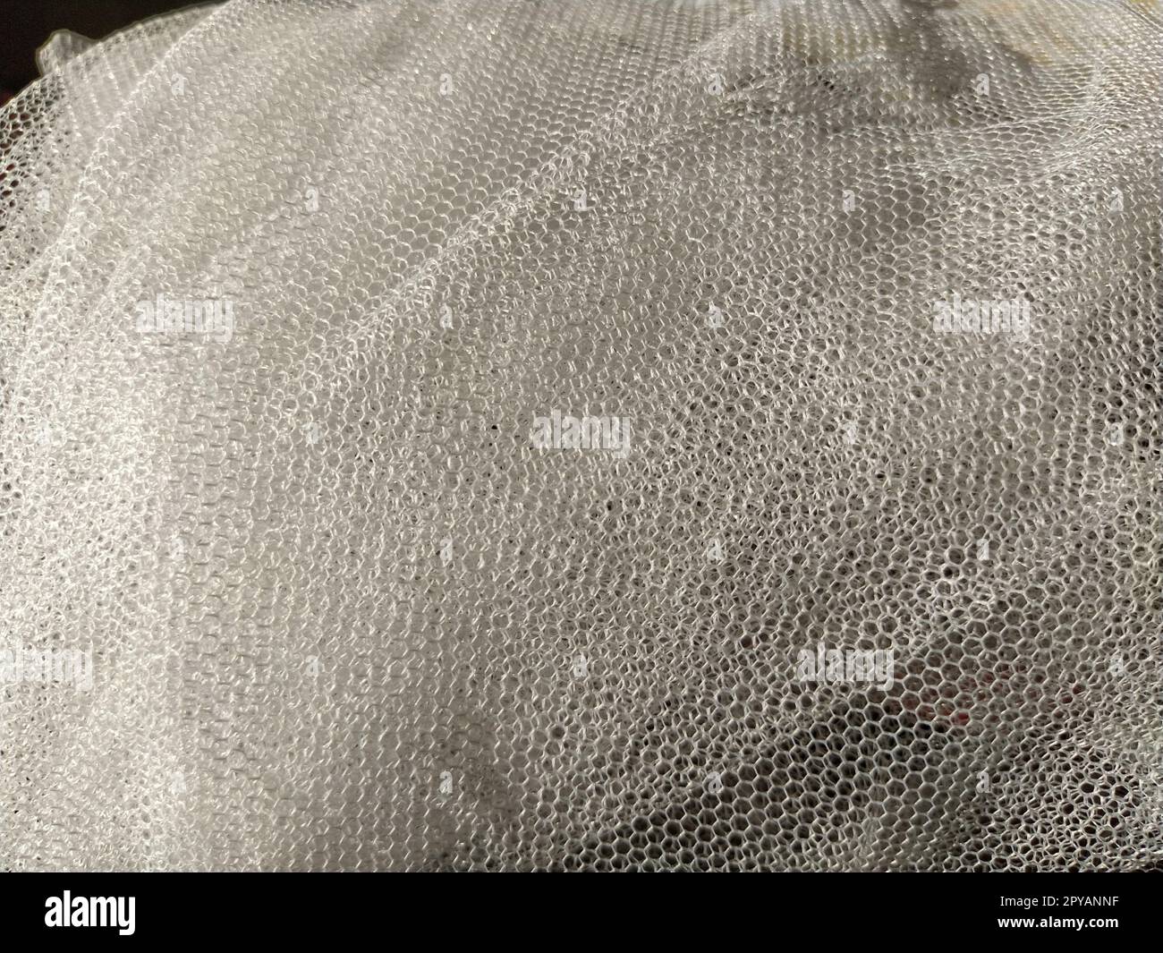 Schlichter weißer netzartiger Tüll. Mesh-Material zerknittert oder unachtsam gefaltet. Nahaufnahme Stockfoto