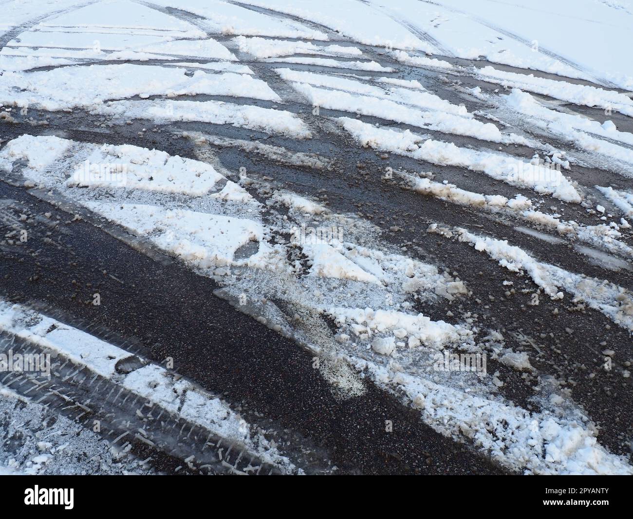 Eine Gabel oder ein Schild aus einem Kreisverkehr. Schneeverwehungen am Straßenrand. Schlechtes Wetter. Schnee auf Asphalt. Schwierige Fahr- und Verkehrsbedingungen. Winterschlamm auf der Straße. Bremsweg eines Autos Stockfoto
