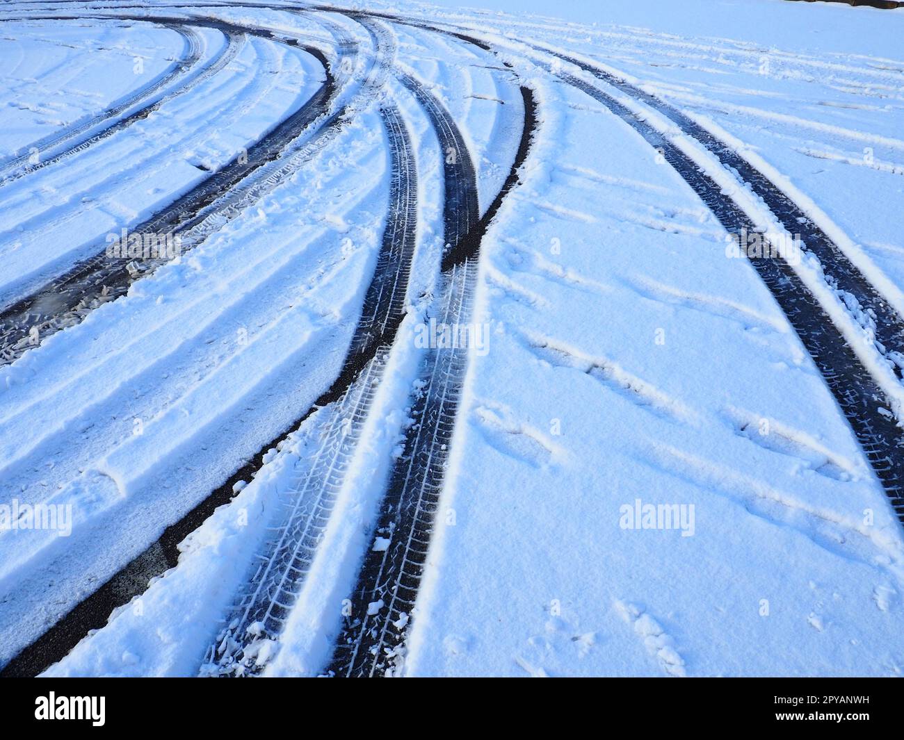 Schneeverwehungen am Straßenrand. Schlechtes Wetter und Verkehr. Schnee auf Asphalt. Schwierige Fahrbedingungen. Winterschlamm auf der Straße. Bremsweg eines Autos. Stockfoto