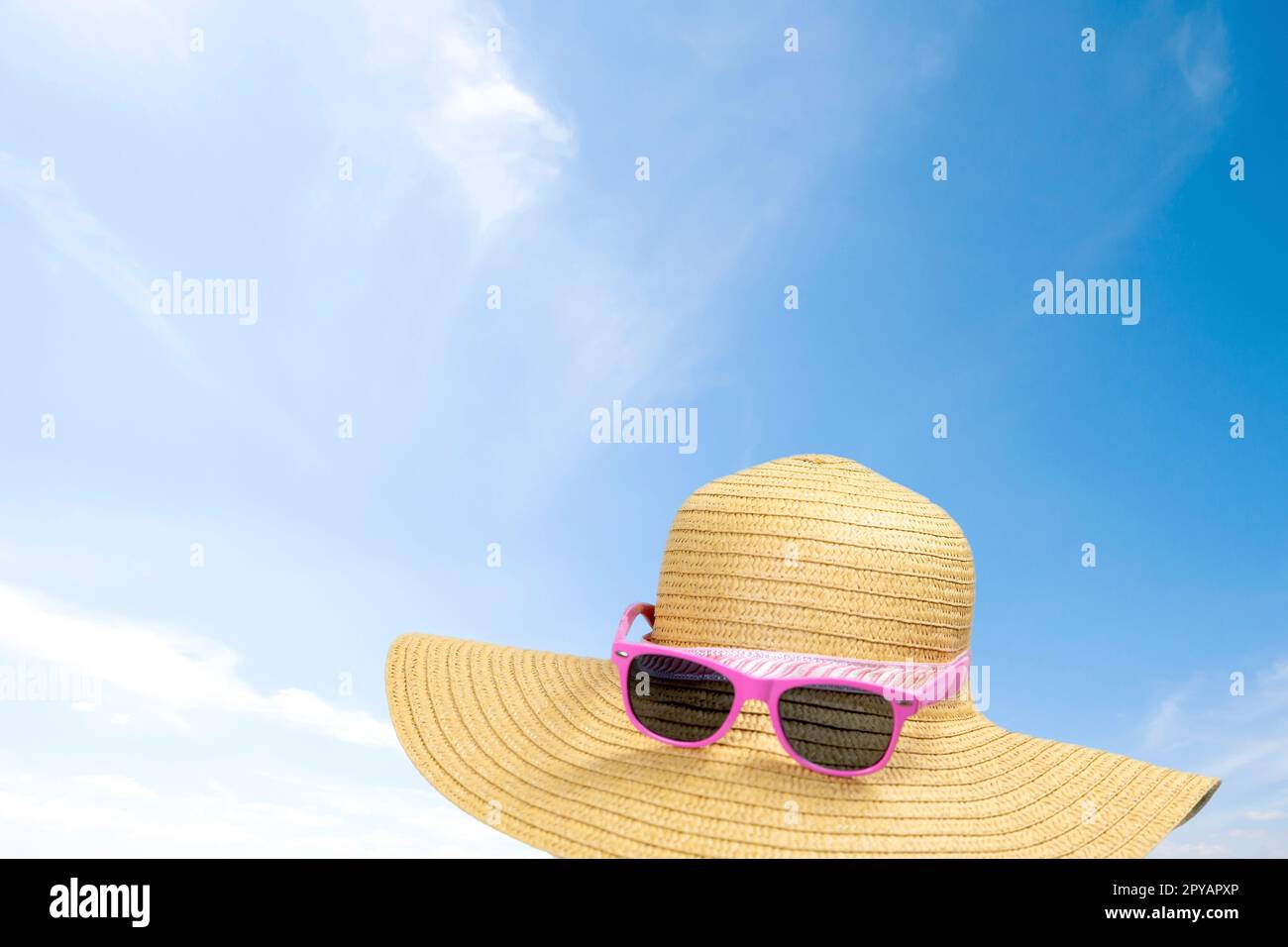 Sommer Sonnenschein Strohhut in blauem Himmel an einem sonnigen Tag. Sonnenbrille Sommerkonzept mit kopierblauem Hintergrund Entspannung, Urlaub, Reisen, Strand, Sonnenkonzept Stockfoto