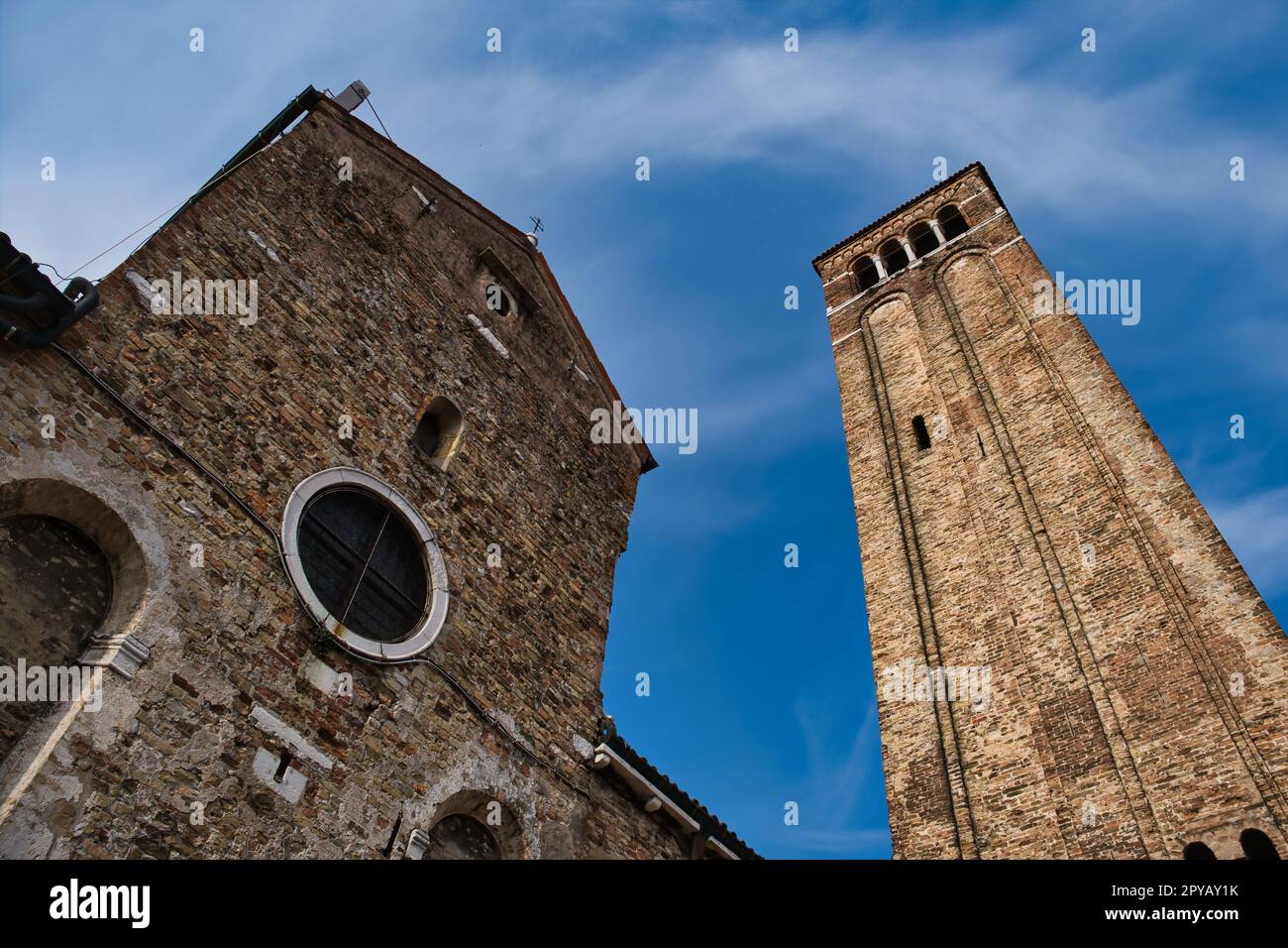 Blick aus dem niedrigen Winkel auf den Glockenturm am Ende der Fassade der Kirche San Giacomo dell'Orio, eine der ältesten Kirchen in Venedig Stockfoto