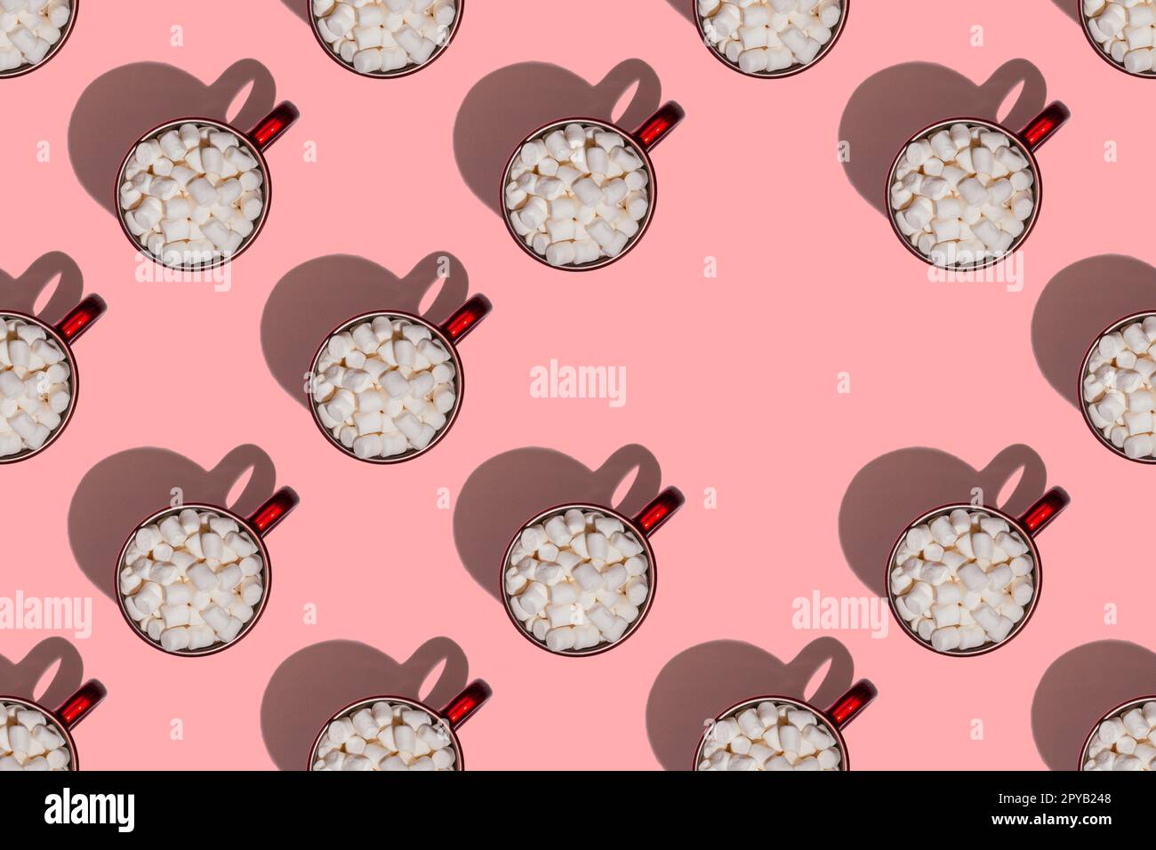 Muster aus roten Tassen mit Kaffee oder Kakao mit Marshmallows mit harten Schatten auf pinkfarbenem Hintergrund. Speicherplatz kopieren Stockfoto