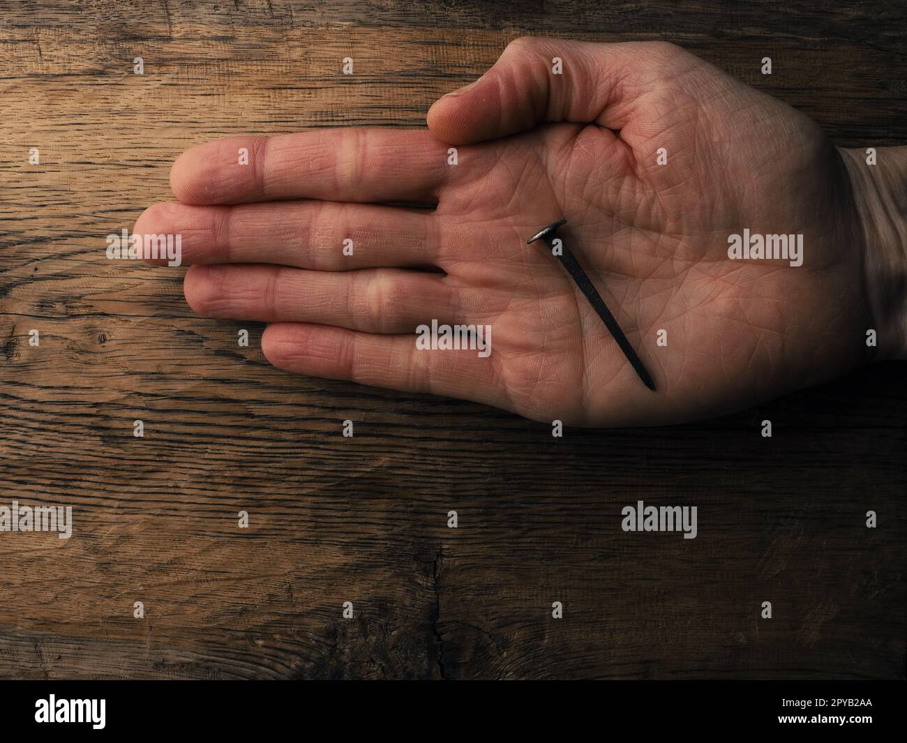 Die Hand mit einem alten rostigen Nagel symbolisiert die Kreuzigung Jesu. Osterkonzept Stockfoto