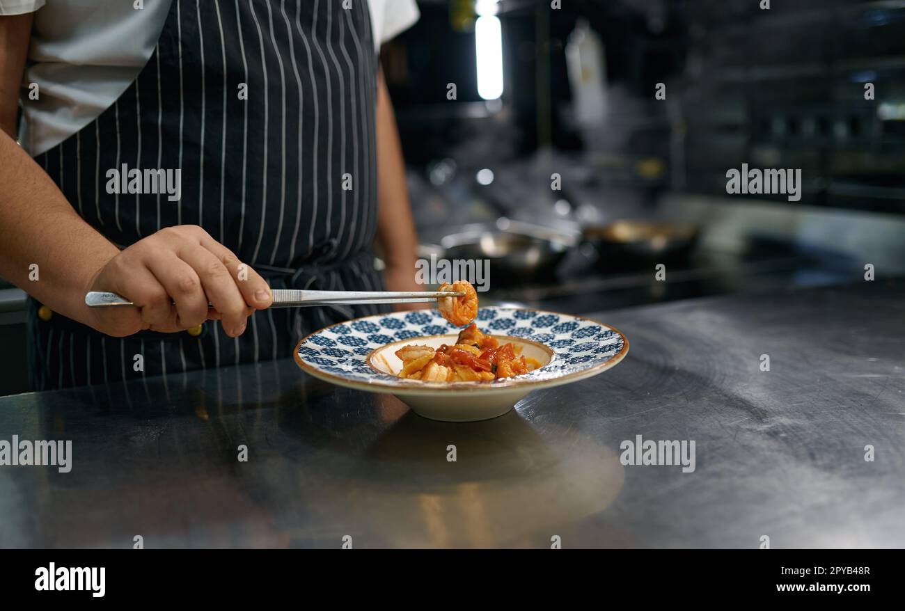 Der Koch legte Spaghetti Carbonara auf den Teller, stand auf der Restaurantküche Stockfoto