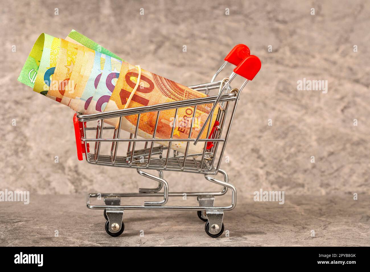 Einkaufswagen aus einem Supermarkt mit einer Rolle Euro-Banknoten Stockfoto