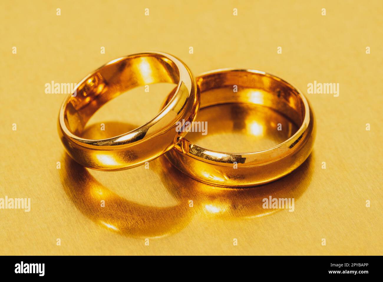 Goldene Eheringe auf einer Metalloberfläche Stockfoto