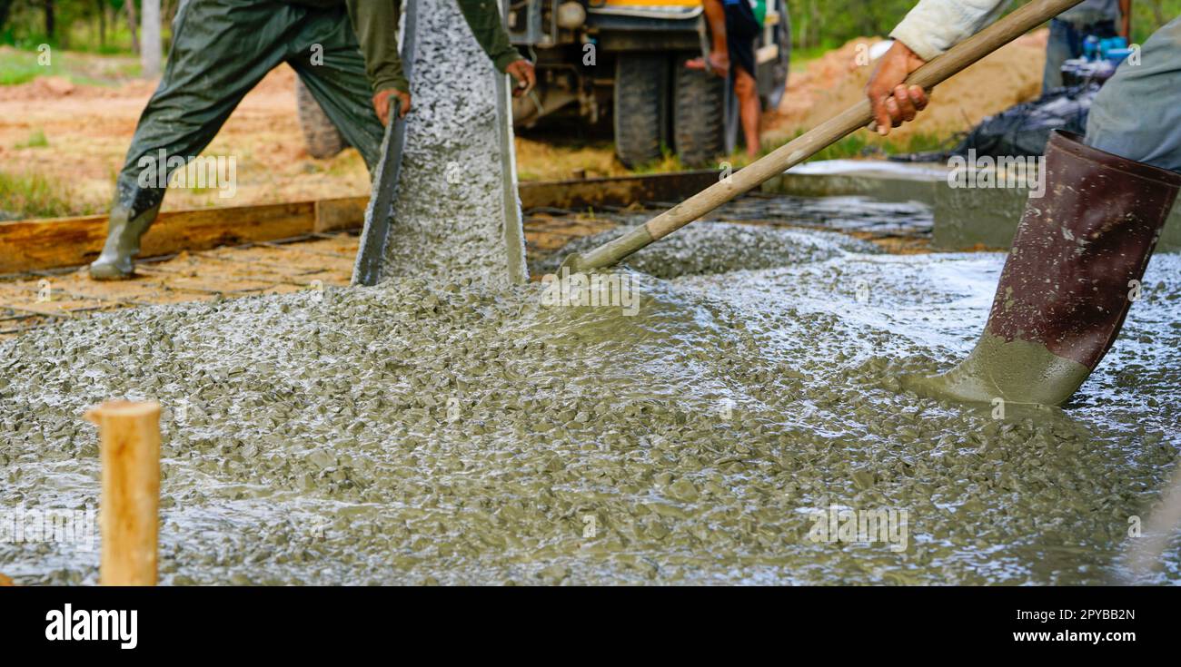 Bauarbeiter gießt nassen Beton auf der Baustelle. Bauarbeiter, der mit Transportbeton aus Zementmischwagen arbeitet. Baukonzessionskonzept. Bauarbeiter gießen Zement. Stockfoto